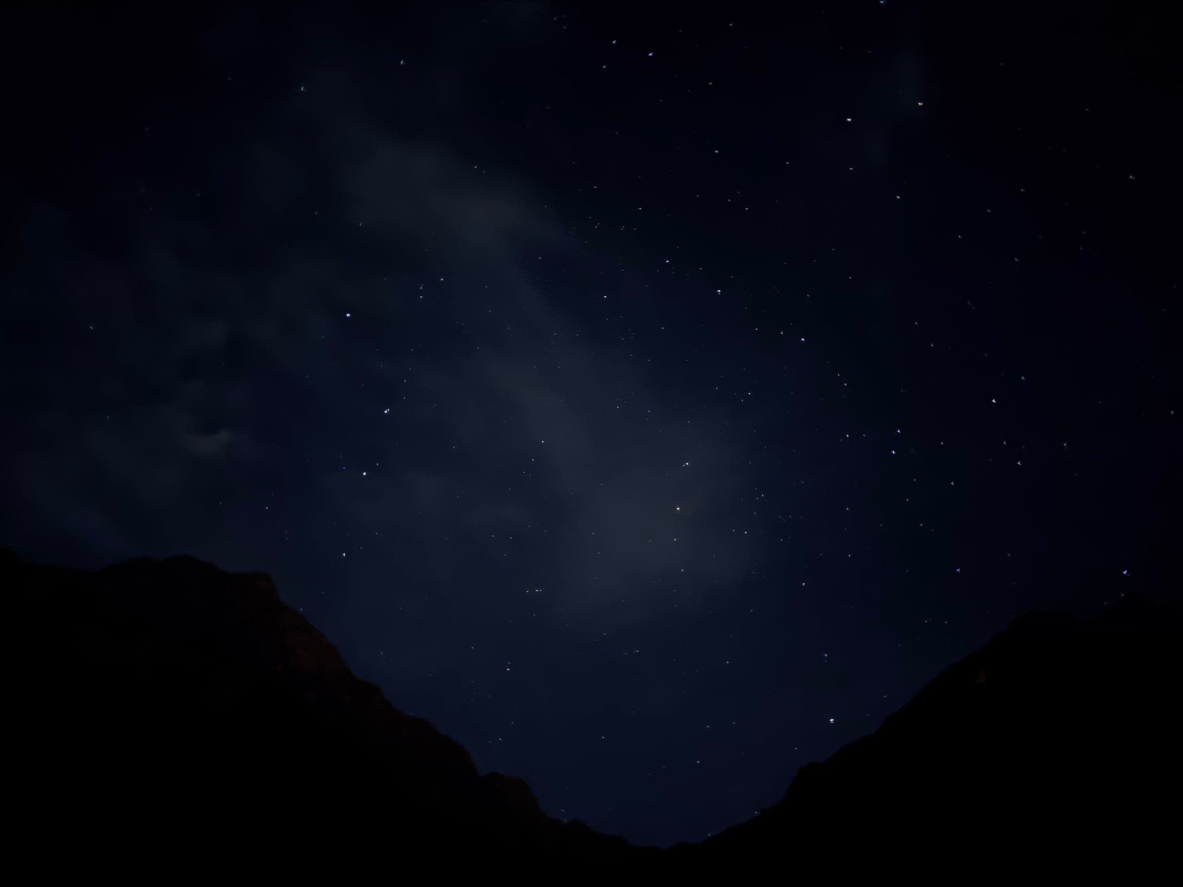Stars and thin cloud above the dark outline of two ridges